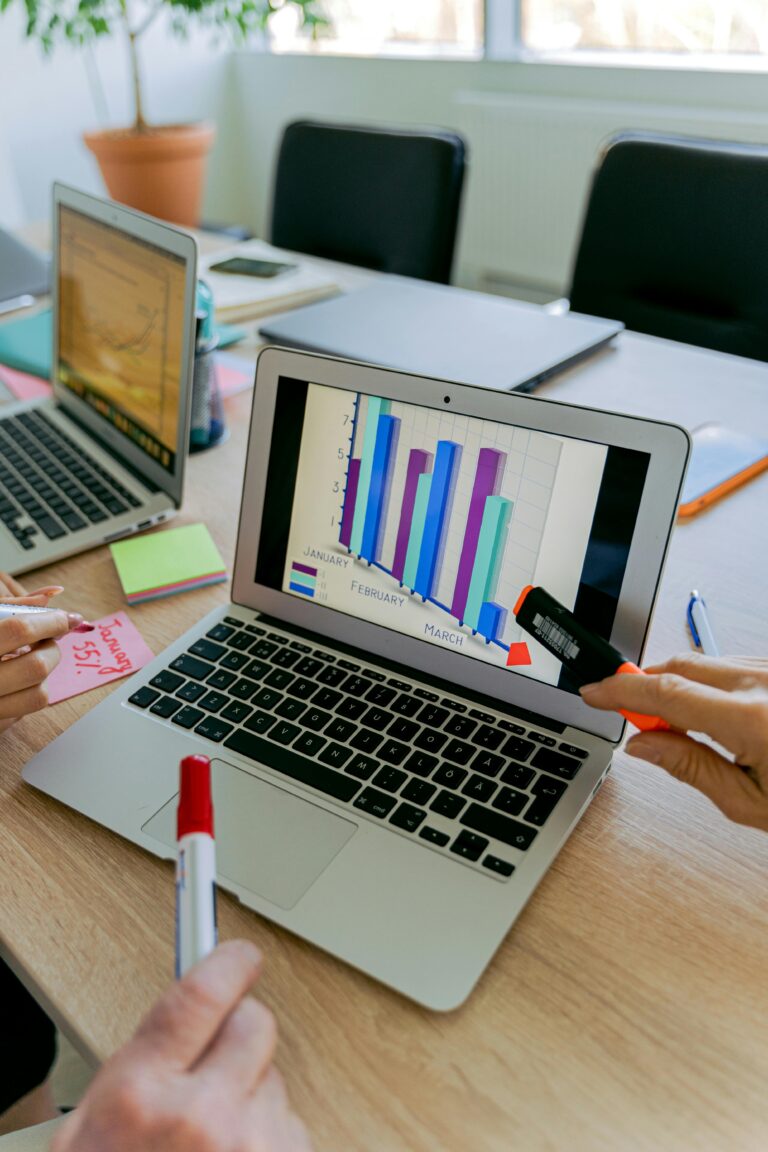 Focused teamwork analyzing a colorful business graph on a laptop screen in a modern office setting.
