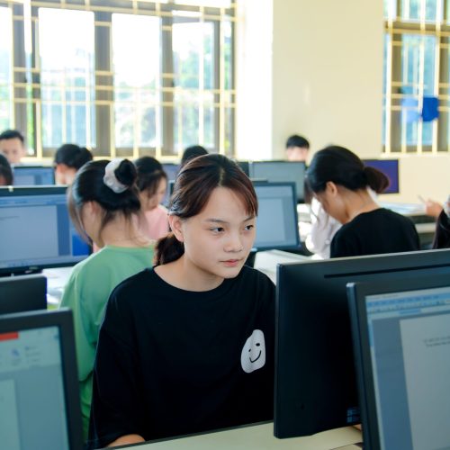 Students focused on computers in a bright classroom setting.
